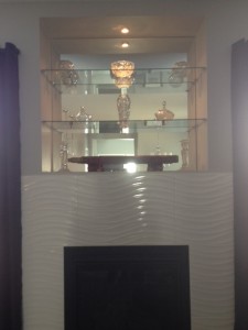 Custom glass shelving above a fireplace