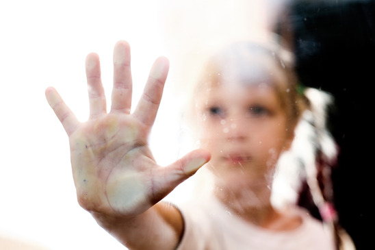 Child holding hand to window